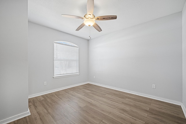 unfurnished room with a textured ceiling, wood finished floors, a ceiling fan, and baseboards