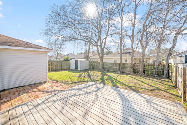 wooden terrace with a yard, a shed, a residential view, a fenced backyard, and an outdoor structure