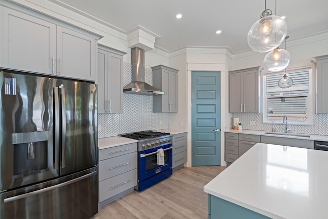 kitchen with range with gas stovetop, stainless steel refrigerator with ice dispenser, light countertops, a sink, and wall chimney range hood