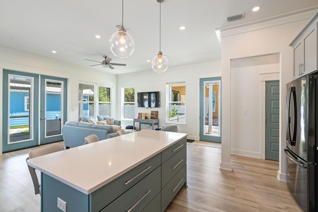 kitchen with open floor plan, a center island, hanging light fixtures, freestanding refrigerator, and light countertops