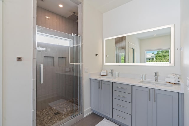 full bath with a stall shower, a sink, recessed lighting, and double vanity