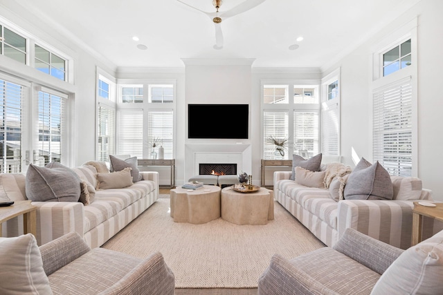 living area featuring a lit fireplace, ornamental molding, and recessed lighting