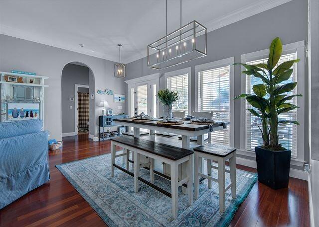 dining area with arched walkways, ornamental molding, dark wood-style floors, and baseboards