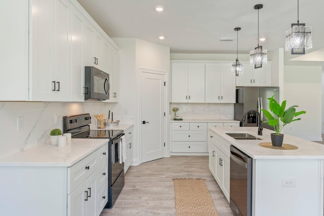 kitchen with a sink, white cabinetry, black appliances, an island with sink, and pendant lighting