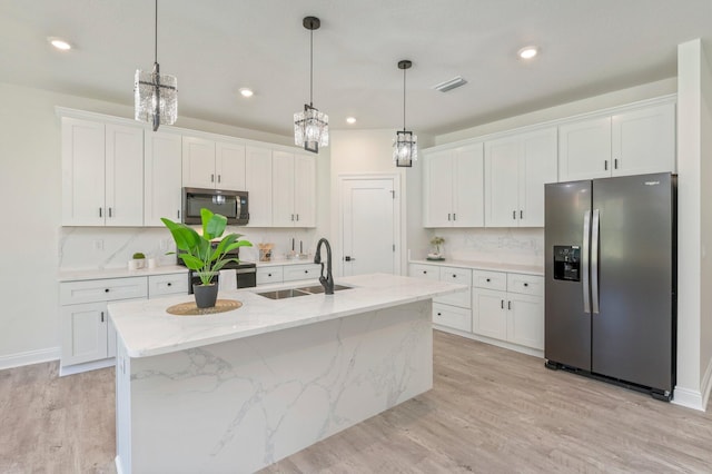 kitchen featuring appliances with stainless steel finishes, a sink, a kitchen island with sink, and white cabinets