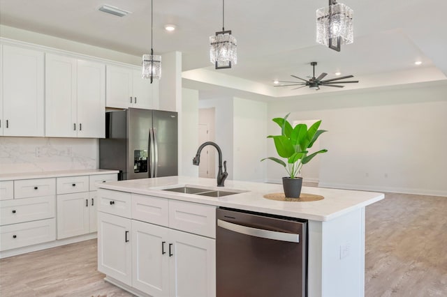 kitchen with stainless steel appliances, a center island with sink, a sink, and white cabinetry