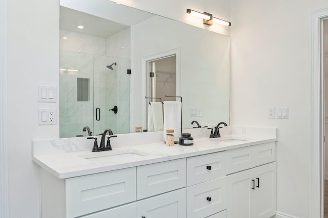 bathroom with a walk in closet, a sink, a shower stall, and double vanity