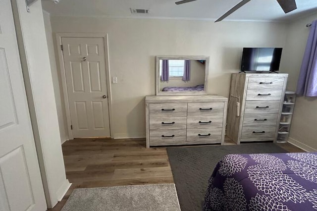 bedroom featuring dark wood-style flooring, crown molding, baseboards, and visible vents