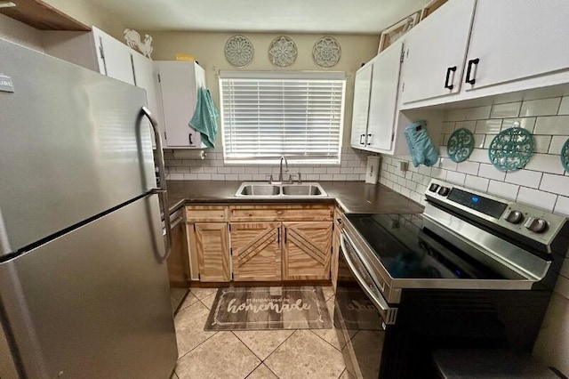 kitchen featuring decorative backsplash, dark countertops, appliances with stainless steel finishes, a sink, and light tile patterned floors
