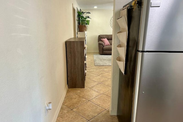 corridor with light tile patterned flooring and baseboards