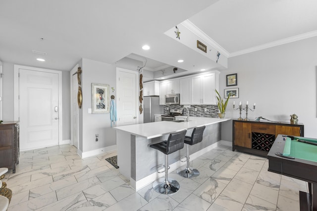 kitchen featuring a peninsula, marble finish floor, stainless steel appliances, white cabinetry, and backsplash