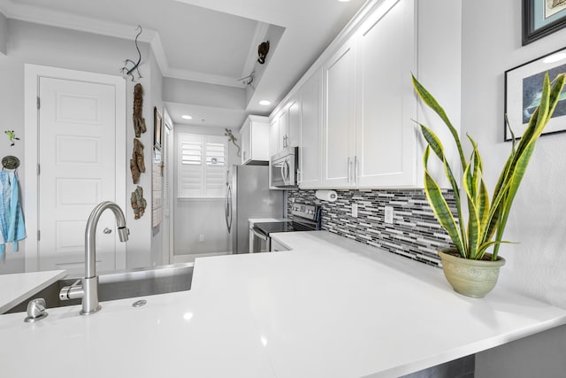 kitchen featuring stainless steel appliances, white cabinetry, light countertops, ornamental molding, and backsplash