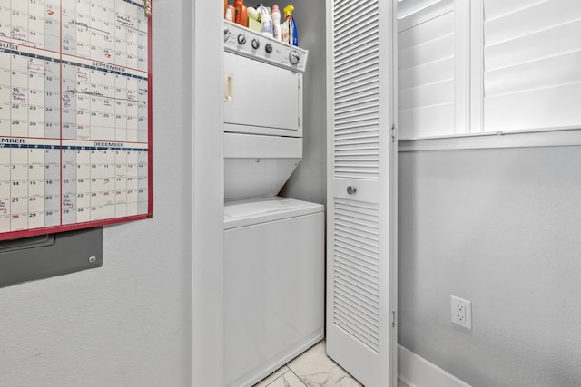 laundry room with laundry area, marble finish floor, and stacked washing maching and dryer