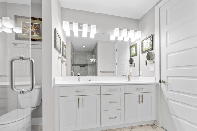 bathroom with double vanity, marble finish floor, a sink, and a stall shower