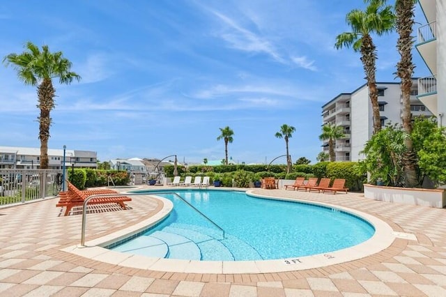 community pool with a patio area and fence