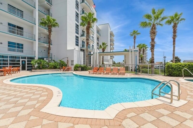 pool with a patio area and fence