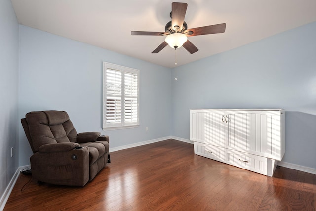 sitting room with dark wood-type flooring, a ceiling fan, and baseboards