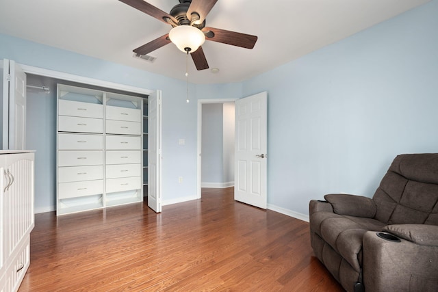 living area with a ceiling fan, baseboards, visible vents, and wood finished floors