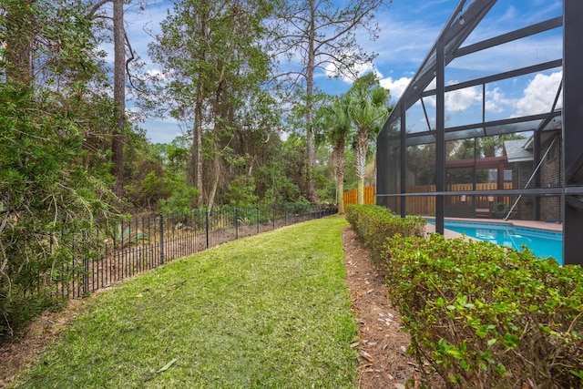 view of yard with glass enclosure, fence, and a fenced in pool