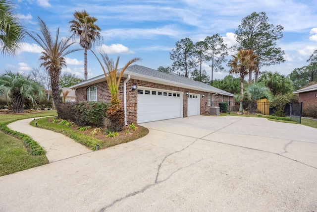 view of home's exterior featuring brick siding, fence, a garage, cooling unit, and driveway