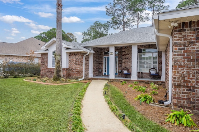 property entrance with a shingled roof, brick siding, and a yard