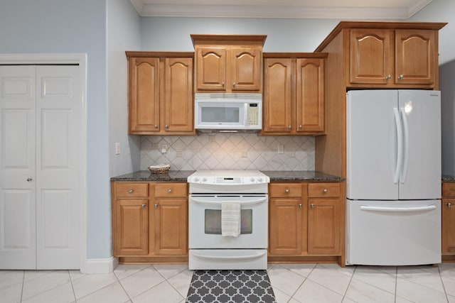 kitchen with white appliances, brown cabinets, crown molding, and dark stone countertops