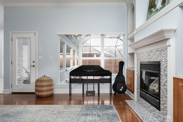 living area with baseboards, dark wood-style flooring, a fireplace, and crown molding