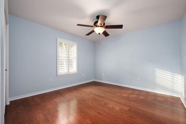 empty room featuring dark wood-style floors, a ceiling fan, and baseboards