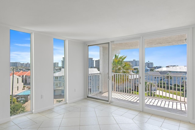 doorway to outside with floor to ceiling windows, a city view, baseboards, and light tile patterned floors