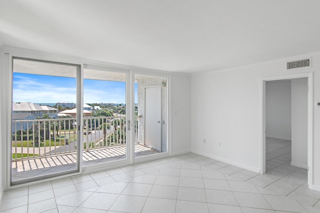 spare room featuring light tile patterned flooring, visible vents, baseboards, expansive windows, and crown molding