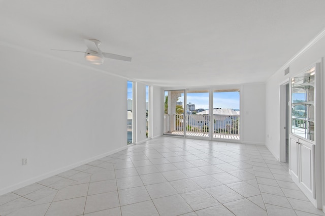 spare room featuring crown molding, light tile patterned floors, visible vents, expansive windows, and baseboards