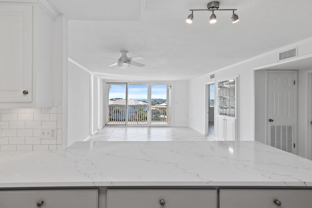 kitchen with tasteful backsplash, visible vents, and light stone countertops