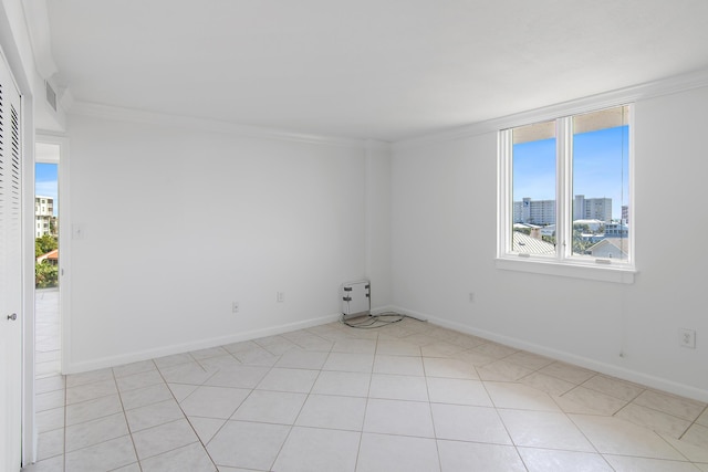 spare room with ornamental molding, a city view, plenty of natural light, and baseboards