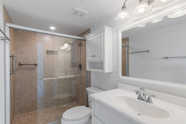 bathroom featuring toilet, a stall shower, visible vents, and vanity