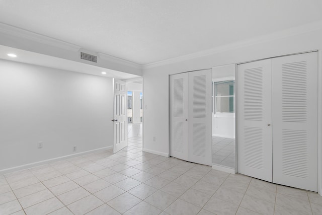 unfurnished bedroom with light tile patterned floors, visible vents, baseboards, multiple closets, and crown molding