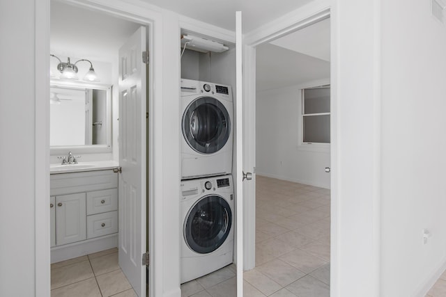 laundry room featuring stacked washer / drying machine, laundry area, a sink, and light tile patterned floors