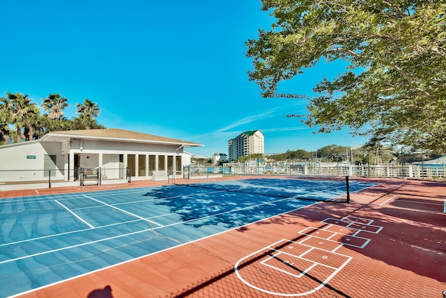 view of tennis court featuring a view of city and fence