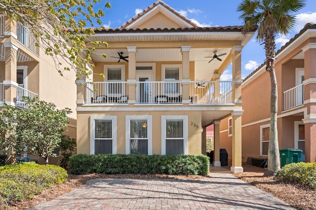 view of front of house with ceiling fan, a balcony, and stucco siding