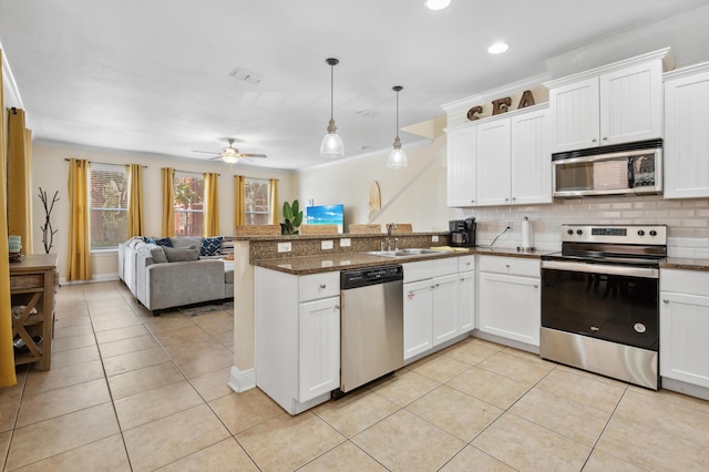 kitchen with open floor plan, a peninsula, stainless steel appliances, white cabinetry, and pendant lighting