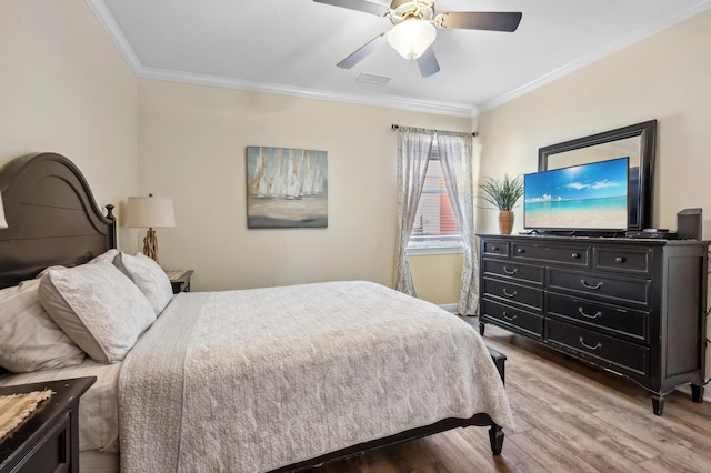 bedroom featuring ornamental molding, visible vents, ceiling fan, and wood finished floors