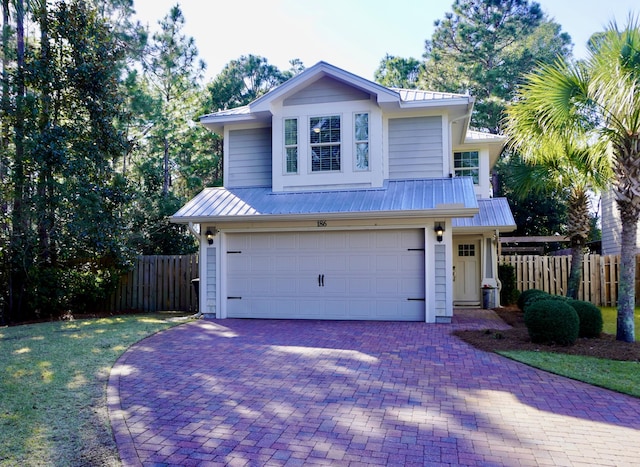 view of front of property with metal roof, decorative driveway, an attached garage, and fence