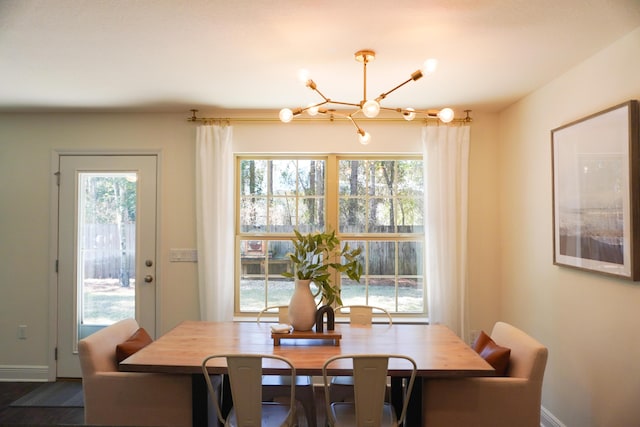 dining space featuring a healthy amount of sunlight, baseboards, and an inviting chandelier