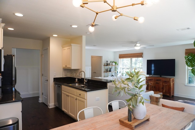 kitchen featuring visible vents, dishwasher, dark countertops, open floor plan, and a sink