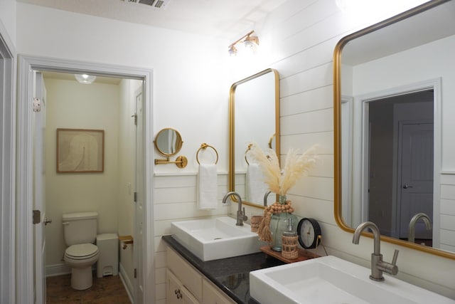 full bathroom with double vanity, a sink, and toilet