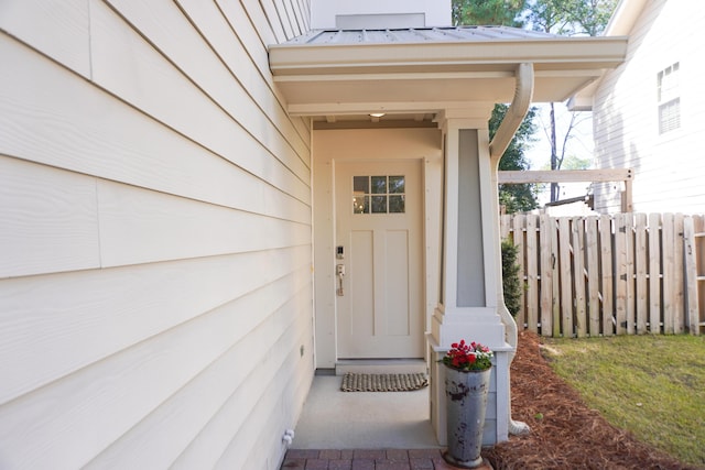 entrance to property featuring a standing seam roof, fence, and metal roof