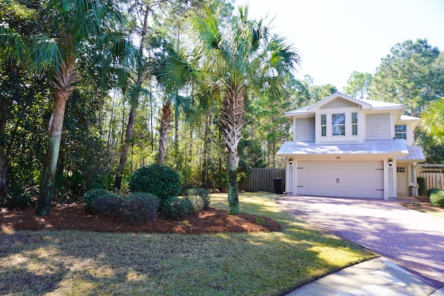 view of front of property featuring an attached garage, fence, metal roof, and decorative driveway