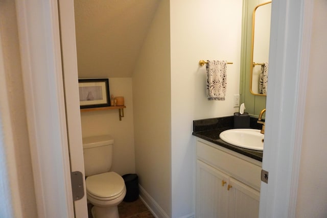 half bathroom with lofted ceiling, tile patterned flooring, toilet, vanity, and baseboards