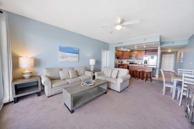 living room with light carpet, ceiling fan, visible vents, and track lighting