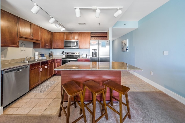 kitchen featuring appliances with stainless steel finishes, a breakfast bar area, light tile patterned flooring, and a center island