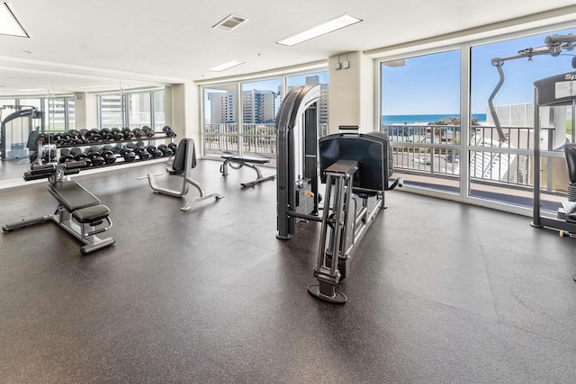 gym with a wall of windows, a water view, and visible vents